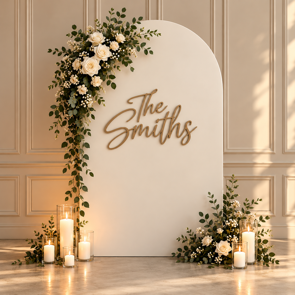 Gold script surname signage styled on a single ivory arch with white flowers